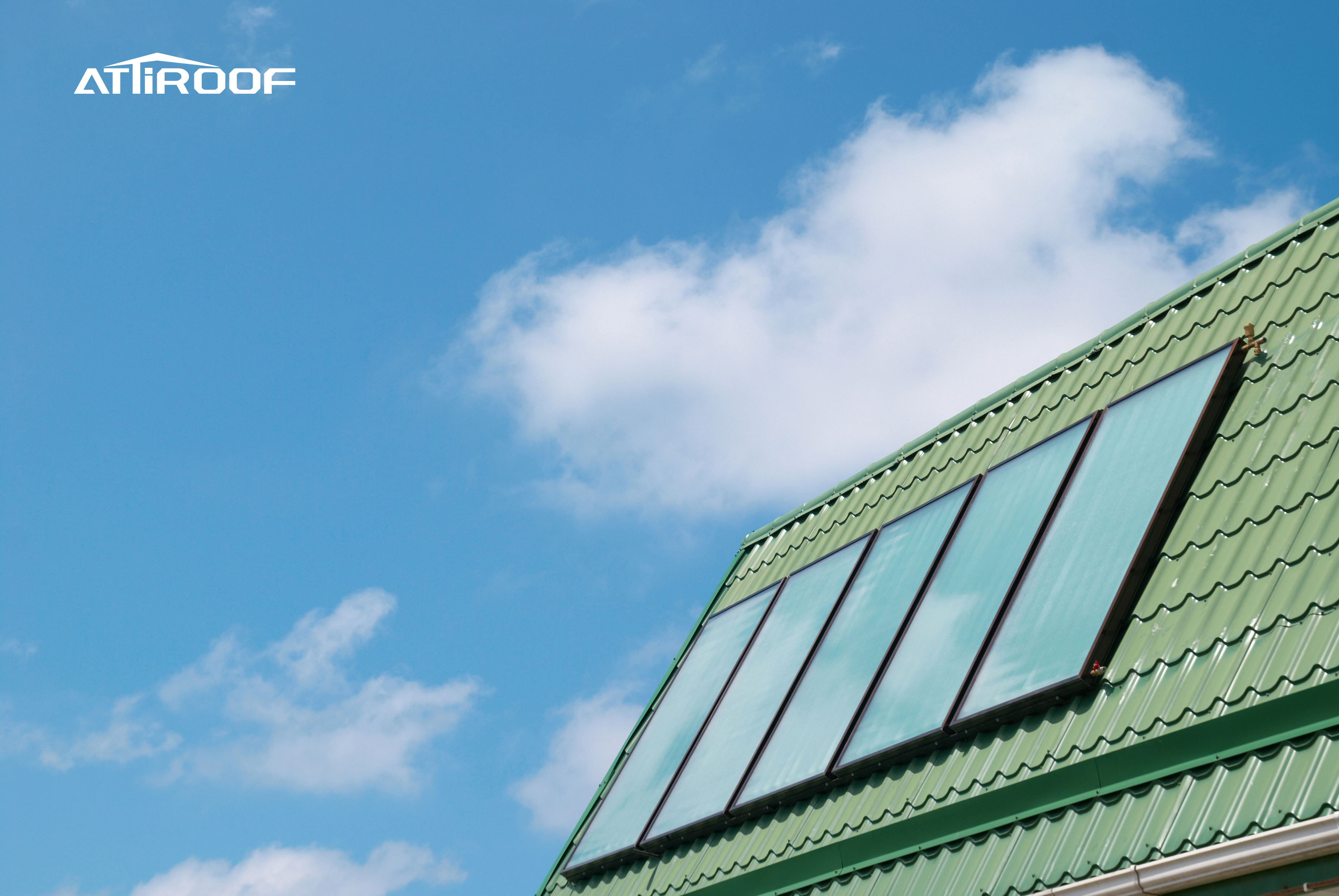 Tejas verdes de resina sintética en un edificio que cumple con los estándares de construcción ecológicos contra un cielo azul con nubes.
