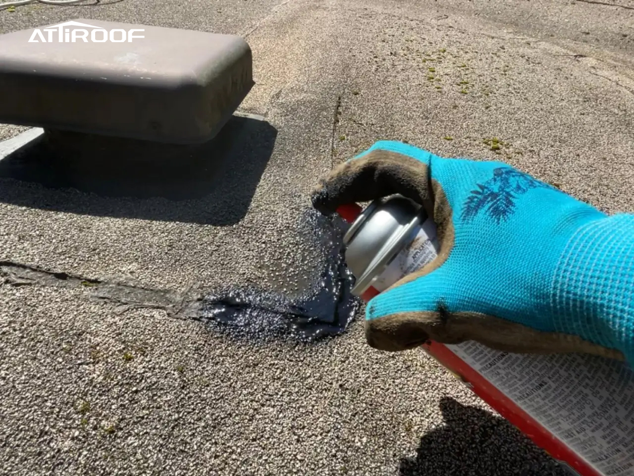 Primer plano de una reparación de techo en curso, que muestra la aplicación de un spray sellador para reparar un área dañada en un techo de tejas.